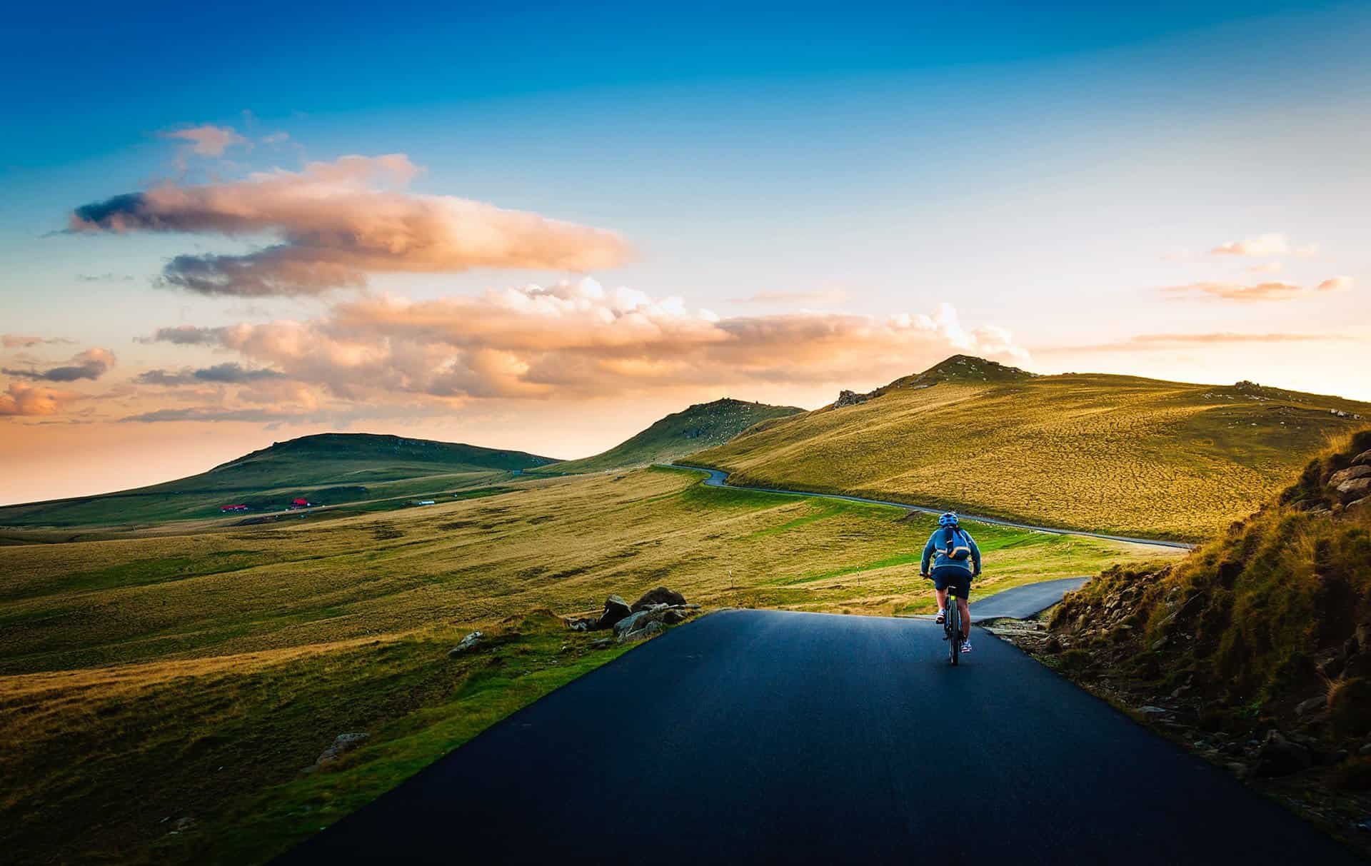 Ciclista su strada panoramica in salita tra le colline toscane al tramonto