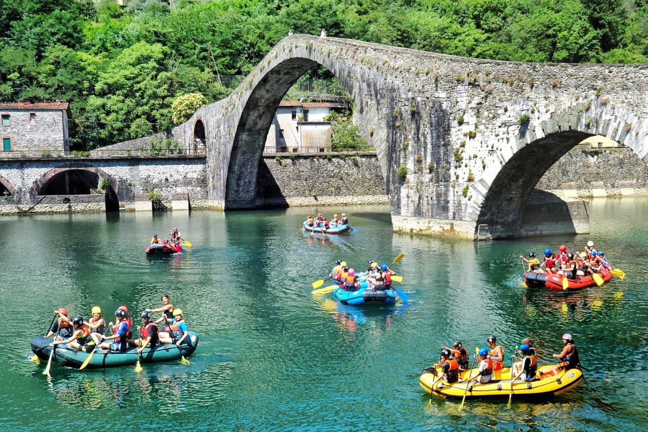 Persone in gommone fanno rafting sul fiume Lima sotto il Ponte del Diavolo, in Garfagnana