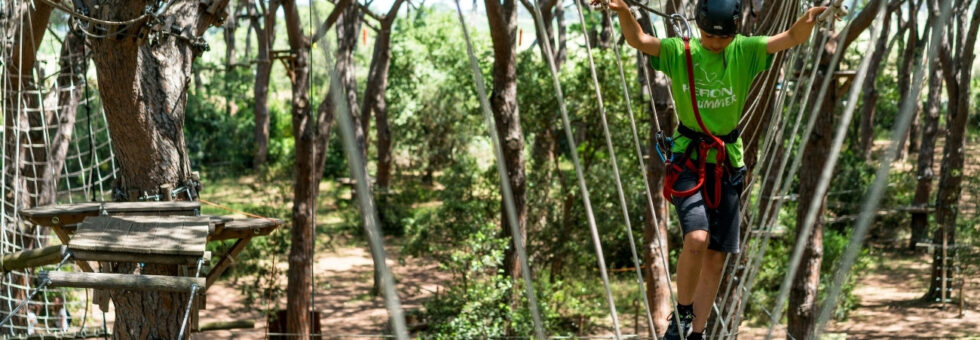 Ponte sospeso con bambino che cerca di attraversalo, al Parco Avventura in Maremma Le Marze