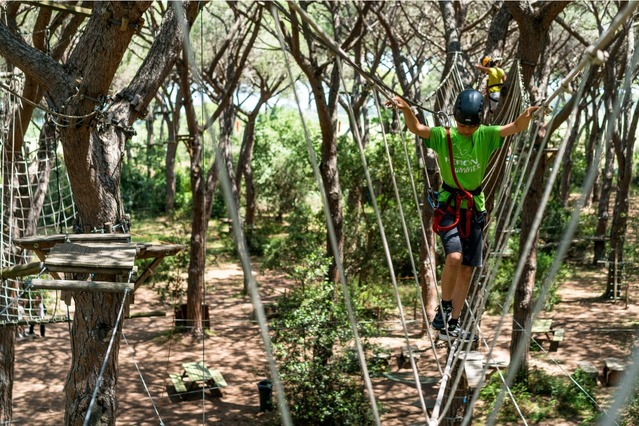 Ponte sospeso con bambino che cerca di attraversalo, al Parco Avventura in Maremma Le Marze