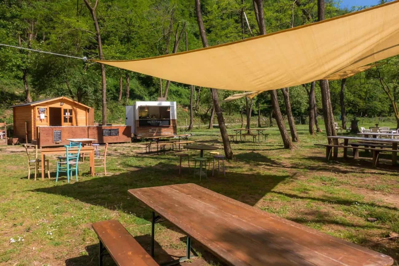 Area ristoro esterna con tavoli in legno all'Agriturismo Pian di Fiume, location perfetta per grigliate e cene rustiche durante un addio al celibato.