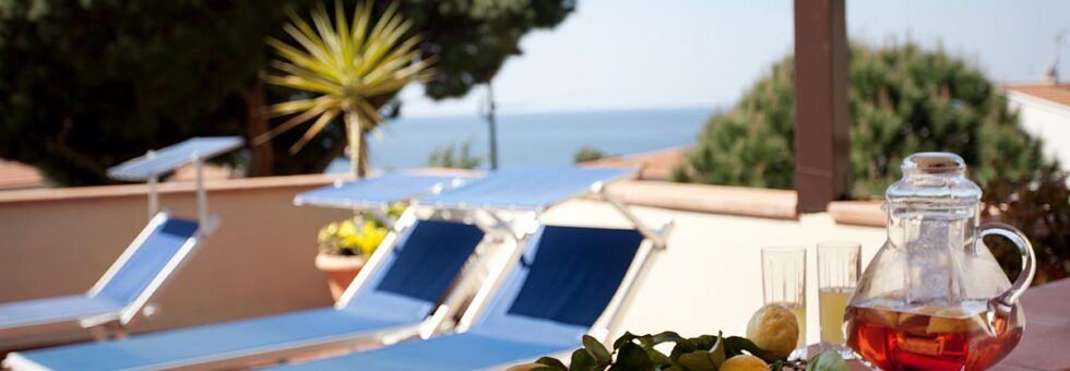 errazza panoramica dell'Hotel Corallo a Pomonte con lettini prendisole, limoni freschi e vista mare sulla Costa del Sole.