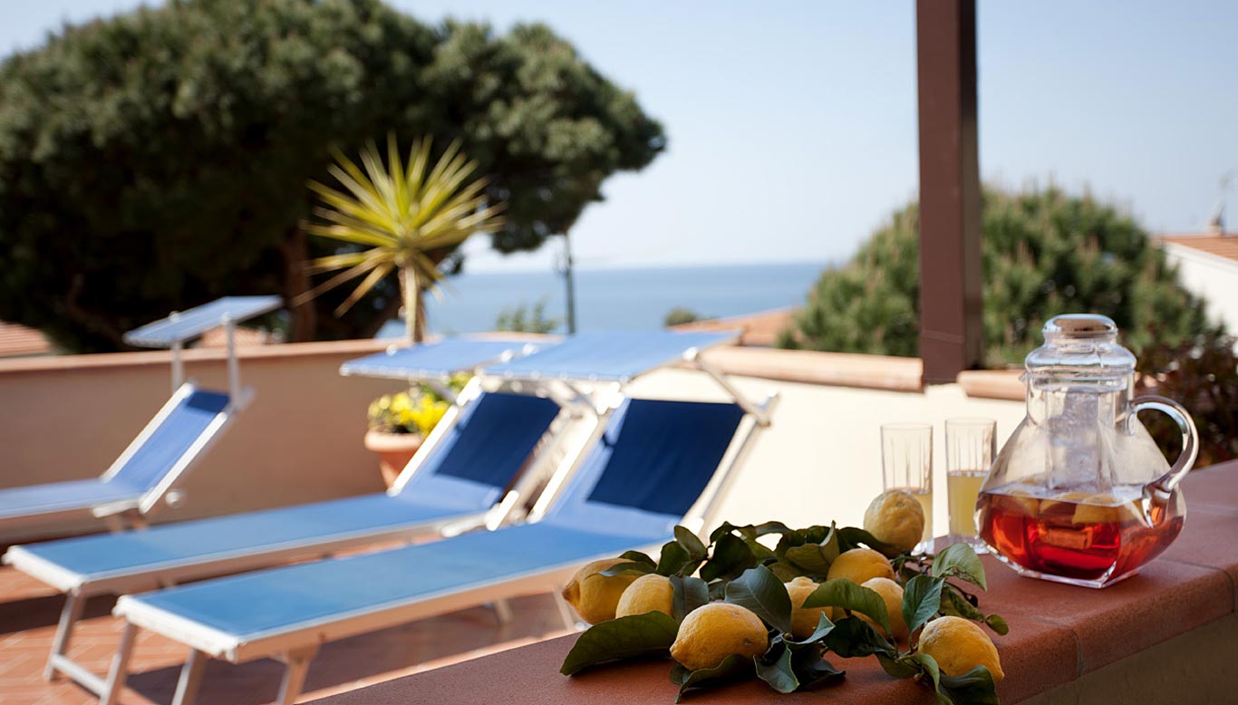 errazza panoramica dell'Hotel Corallo a Pomonte con lettini prendisole, limoni freschi e vista mare sulla Costa del Sole.