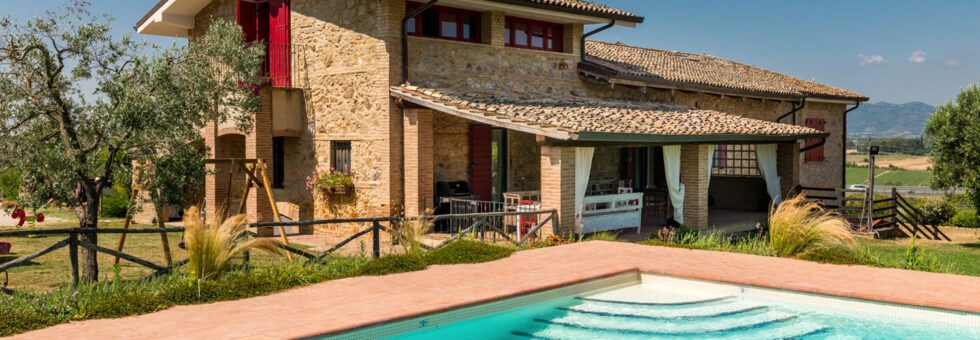 Il casale in pietra ottocentesco del B&B Nonna Nara a Braccagni con la piscina azzurra e il giardino della Maremma grossetana