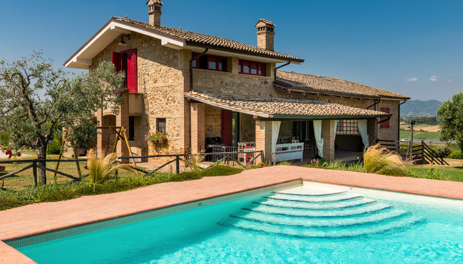 Il casale in pietra ottocentesco del B&B Nonna Nara a Braccagni con la piscina azzurra e il giardino della Maremma grossetana